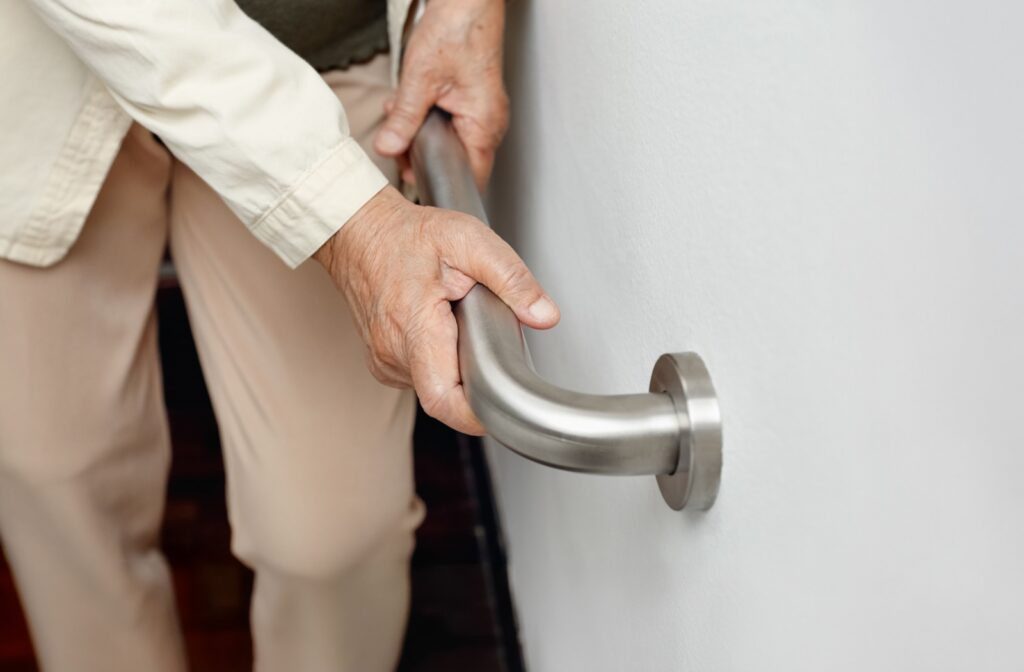 An older adult grabbing onto a handrail.