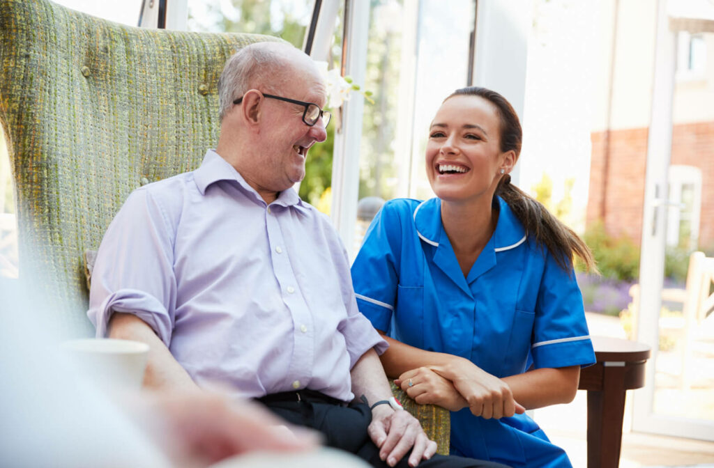 a carer speaks to a senior sitting on a couch