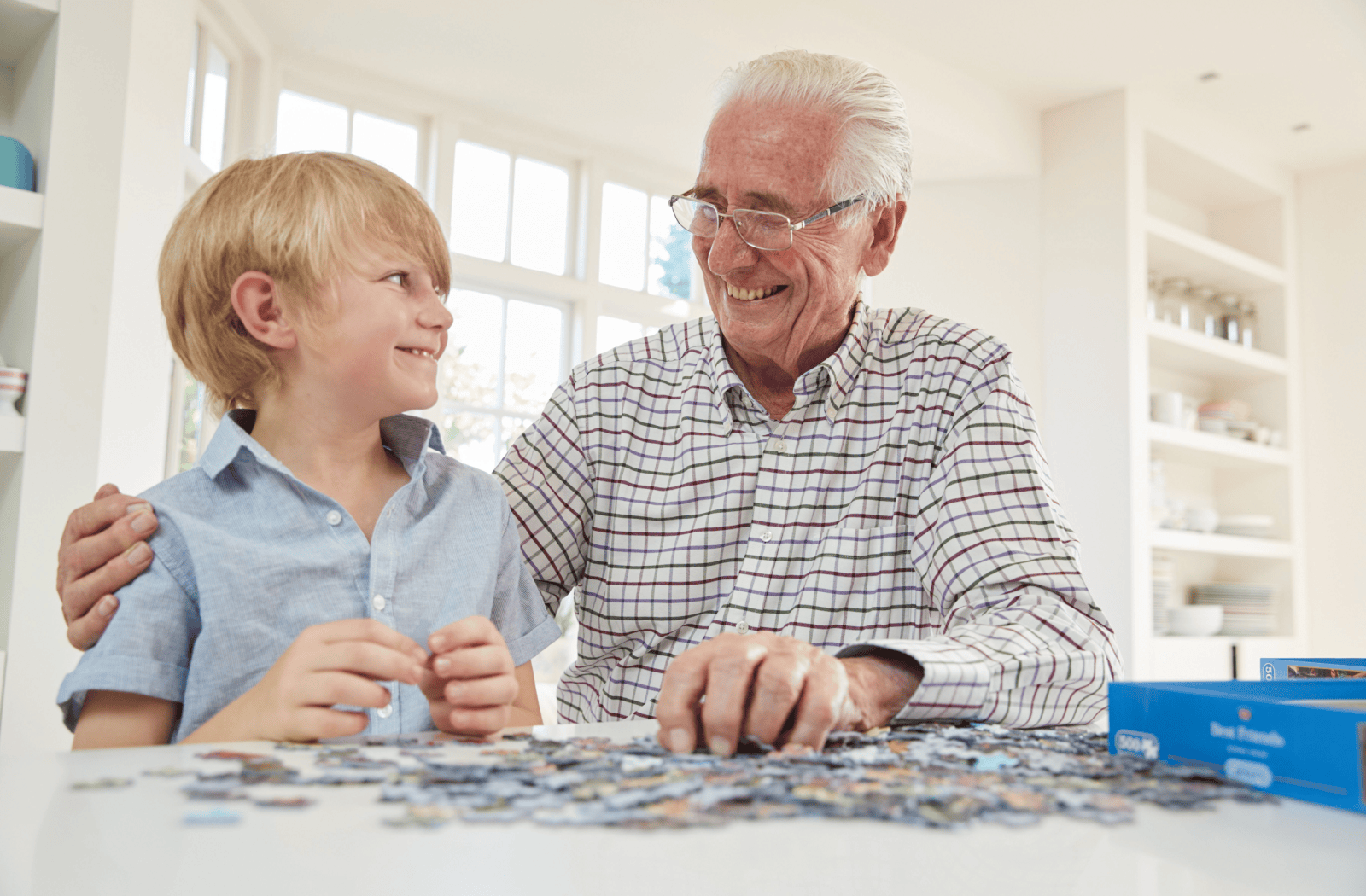 A senior works on a puzzle with their grandchild.