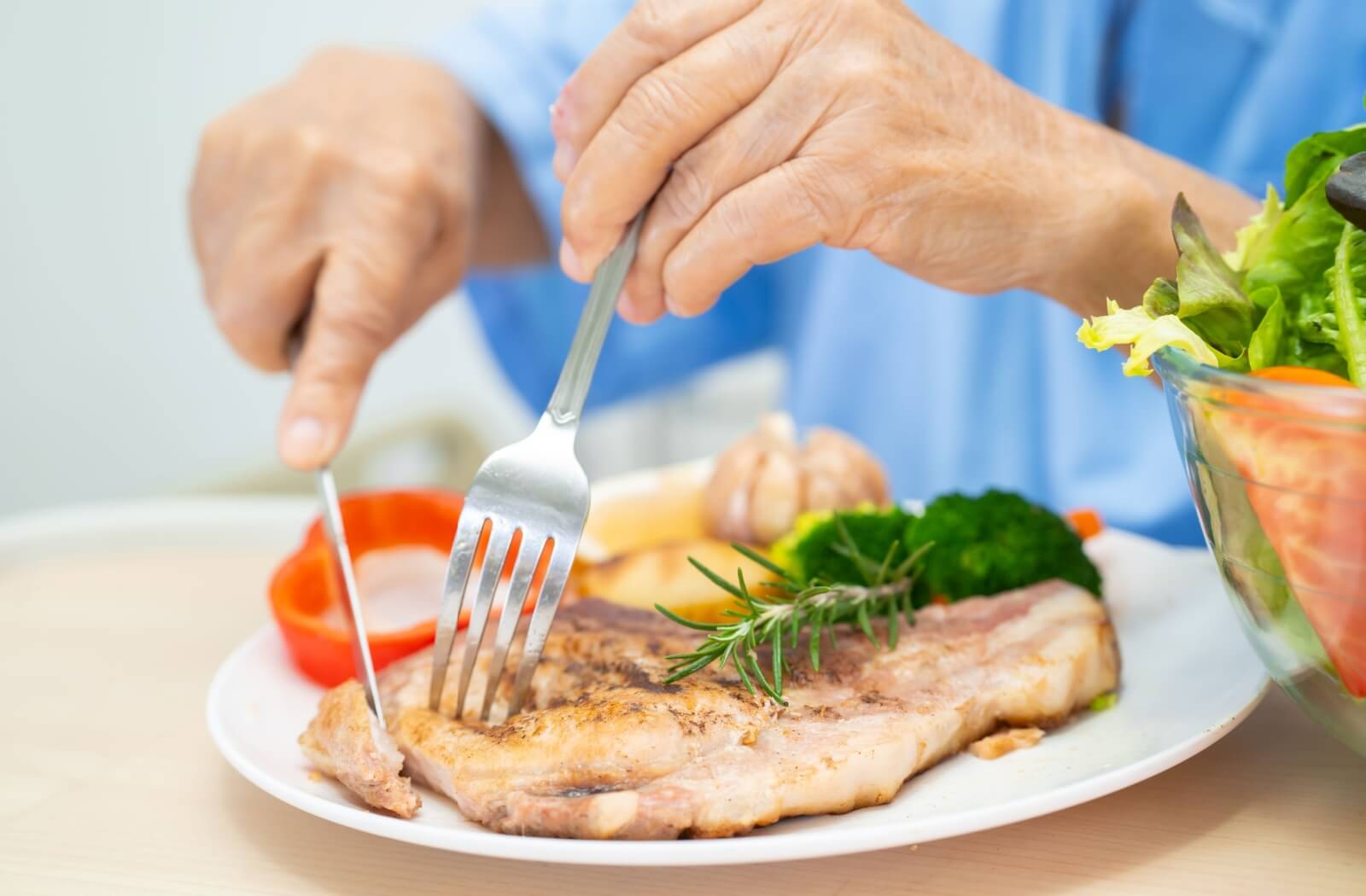 A close-up image of a senior digging into a healthy, colorful meal.