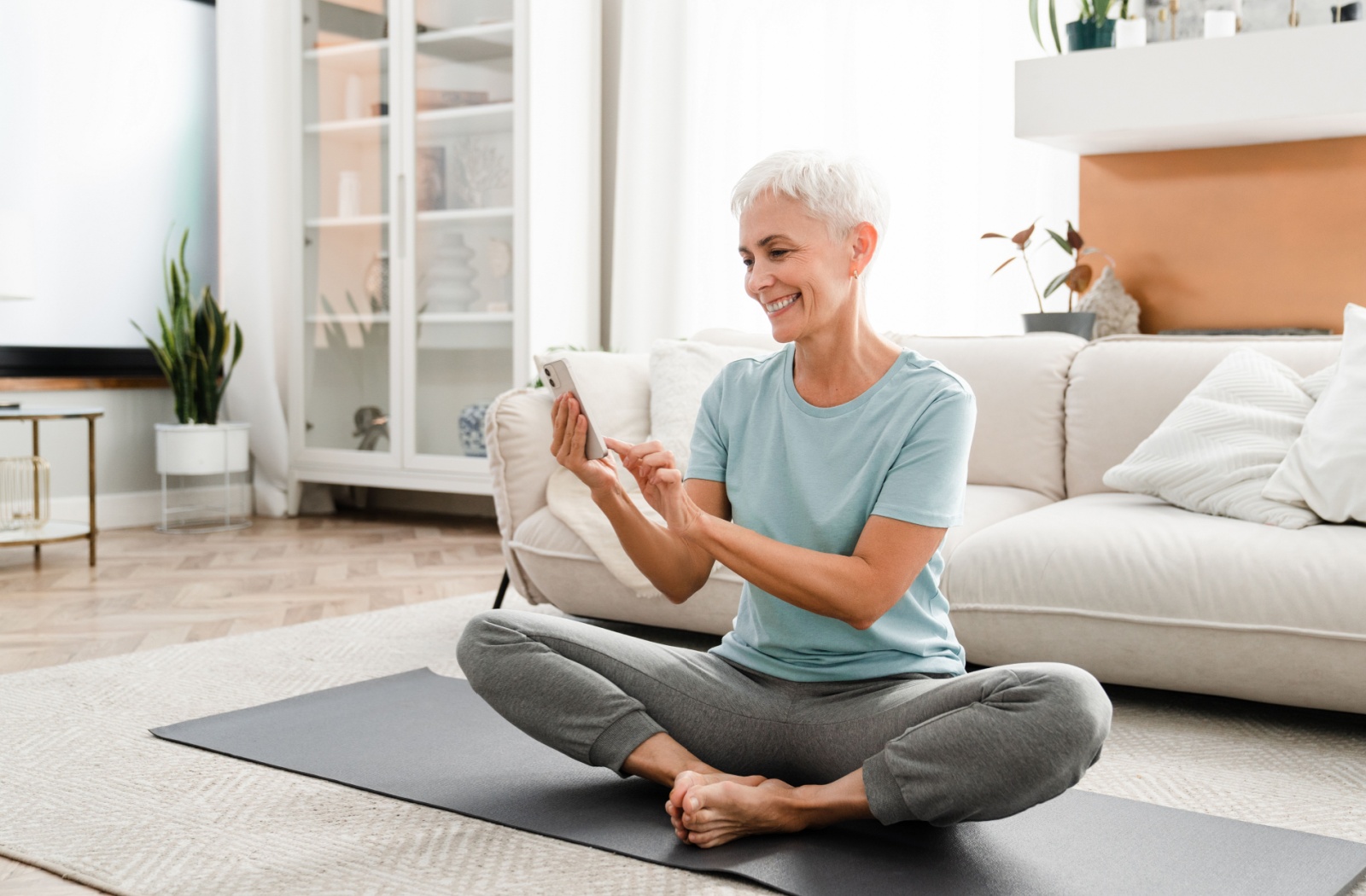 An older adult woman using a yoga fitness app.