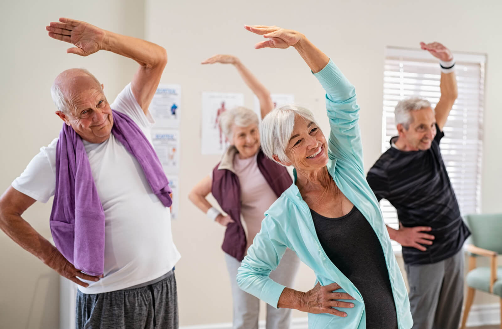 A group of seniors in an exercise class having fun while stretching their arm overhead.