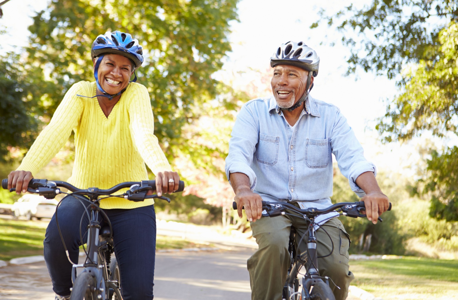 A pair of seniors riding bicycles together outside