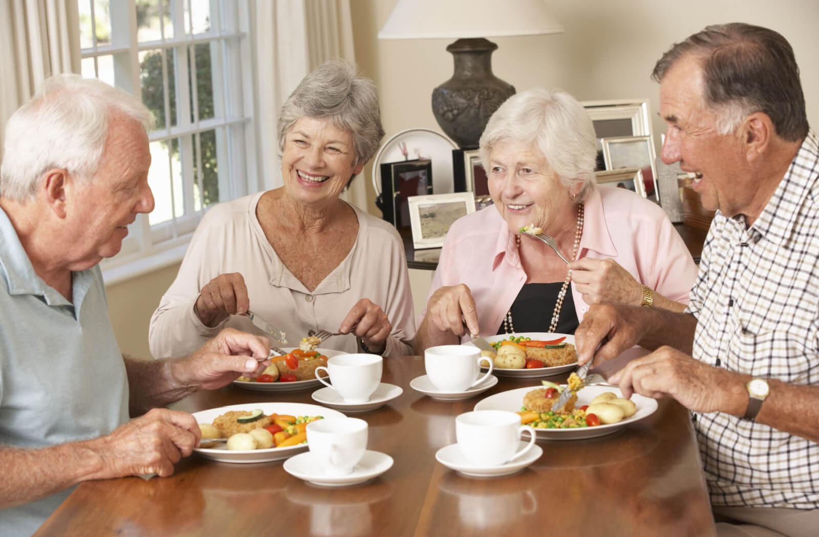 four seniors sit at a table eating a meal together