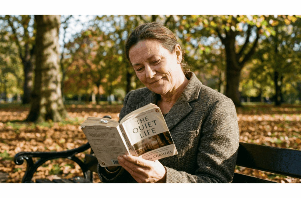A person sits alone on a park bench reading a book, surrounded by trees and sunlight, enjoying a quiet break.